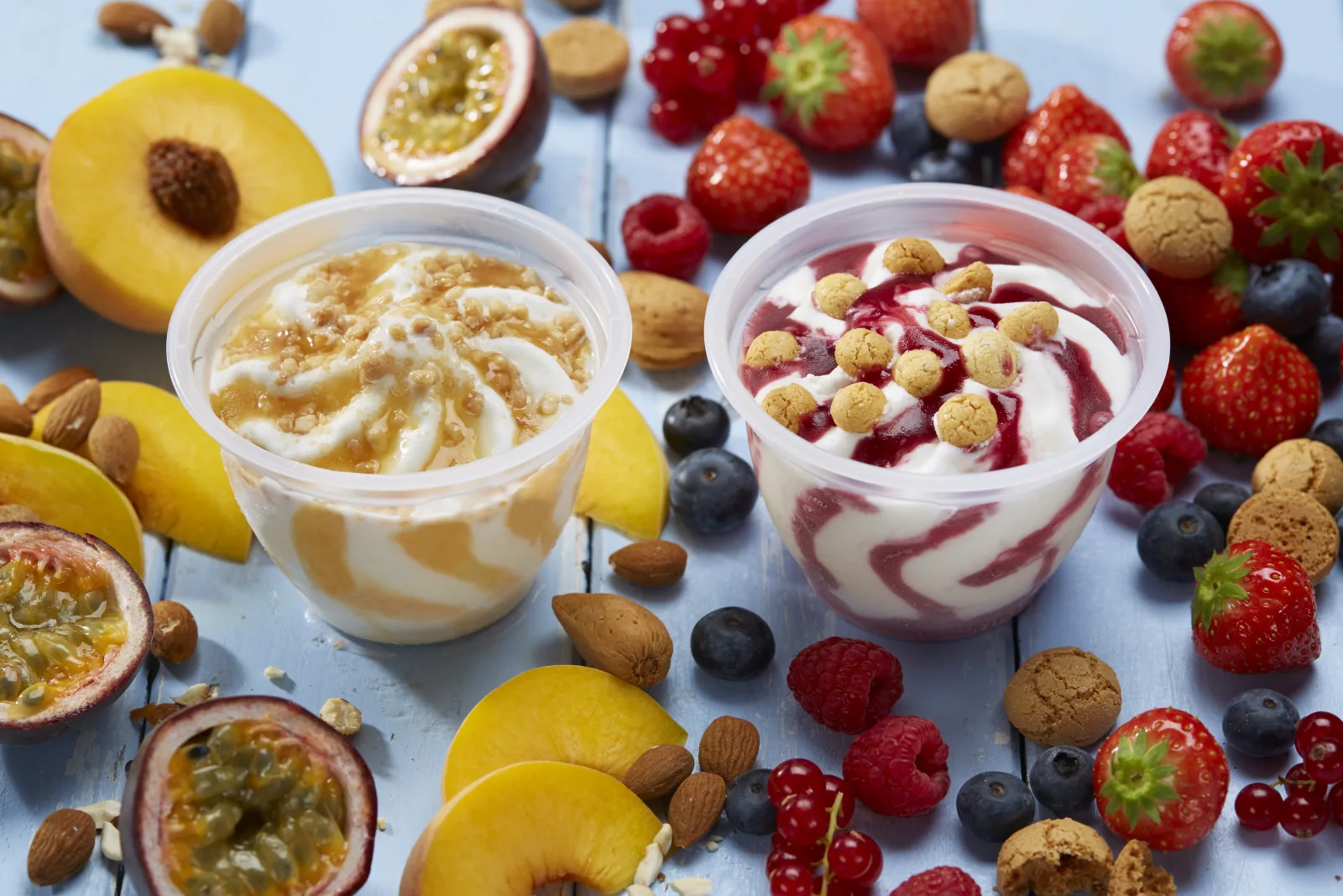 Eisbecher mit Karamell-Pfirsich- und Beeren-Topping neben frischem Obst