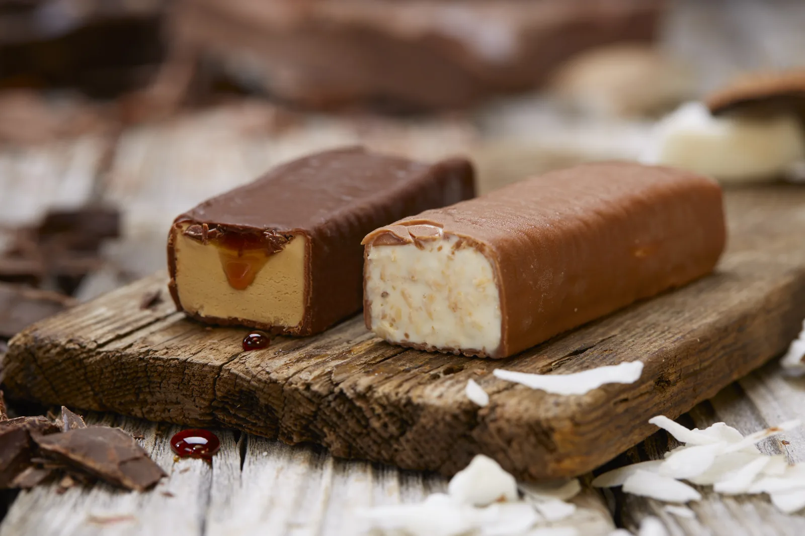 Zwei angeschnittene Schokoladen-Eisriegel mit Karamell- und Kokosf&uuml;llung