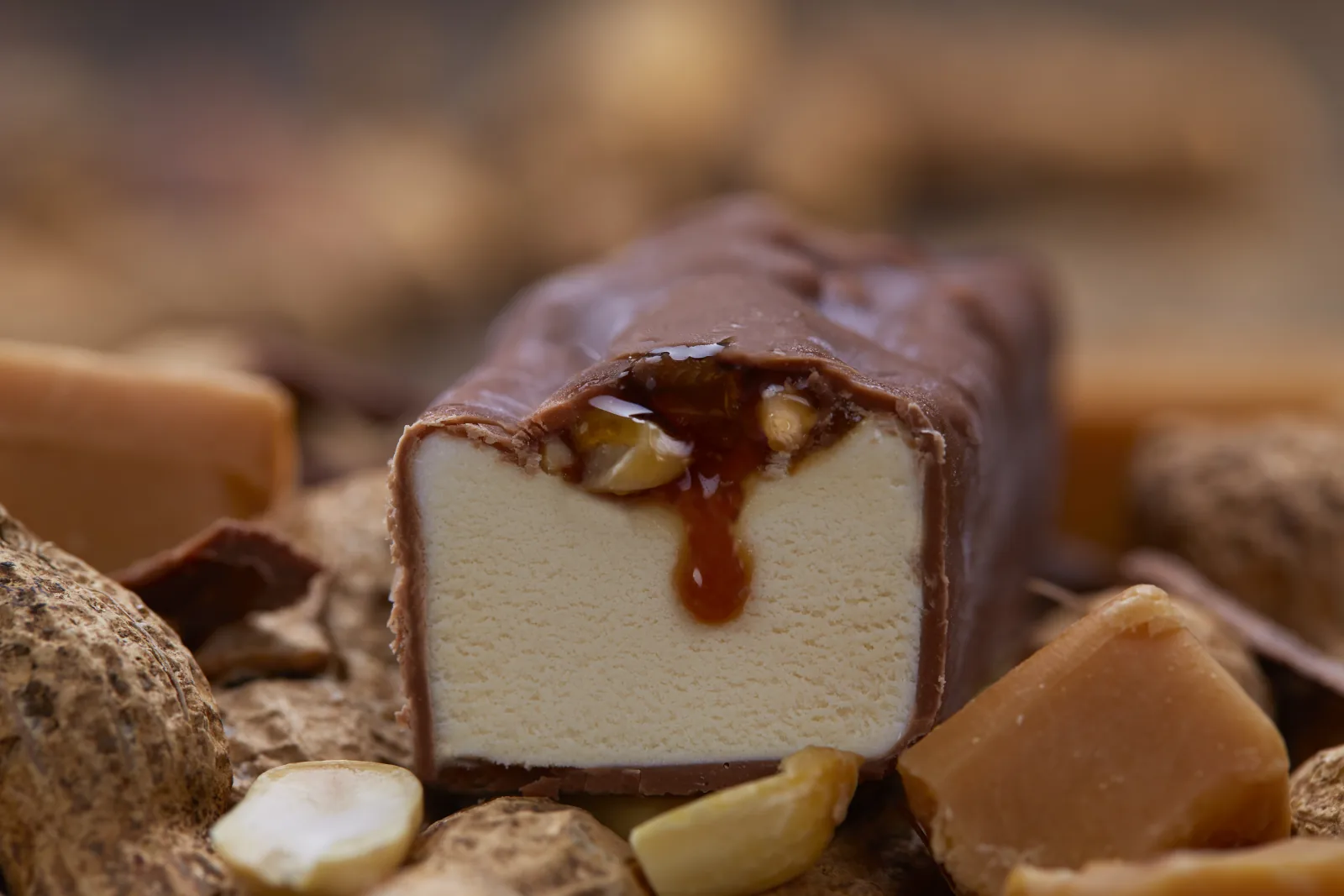 Schokoladen-Eisriegel mit Karamellsauce und Erdnuss-F&uuml;llung in Nahaufnahme